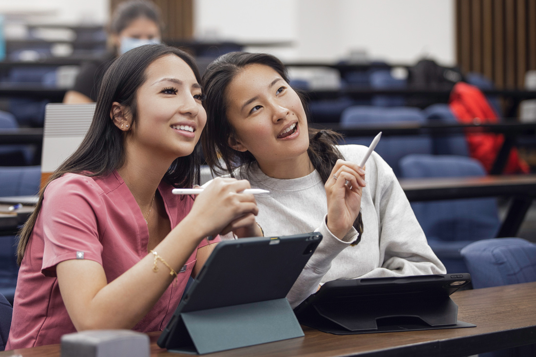 Students smiling in a classroom pointing at a screen