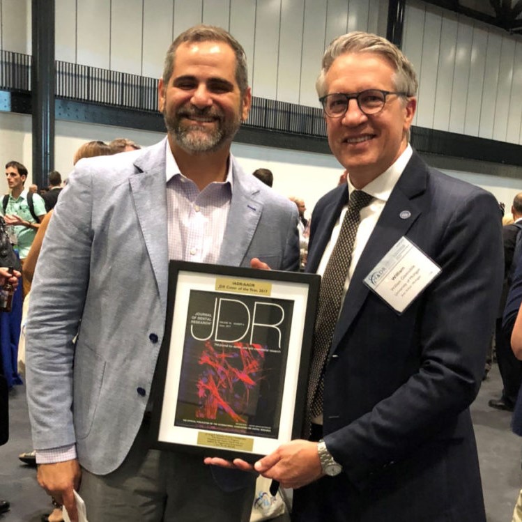 Anibal Diogenes, D.D.S., M.S., Ph.D., (left) receives the Journal of Dental Research Cover Award from editor-in-chief William Giannobile, D.D.S., M.S., D.M.Sc. An illustration of Dr. Diogenes and his team's research on tooth regeneration was selected for the June 2017 edition.