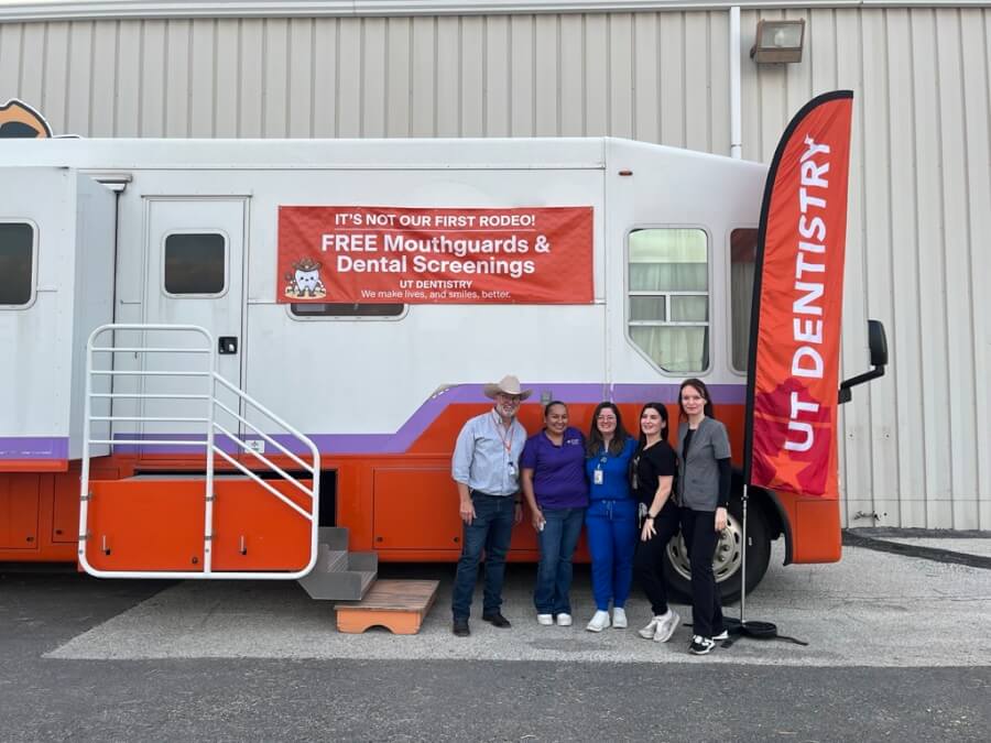 Volunteers from the School of Dentistry stand for a photo in front of the mobile dental clinic.