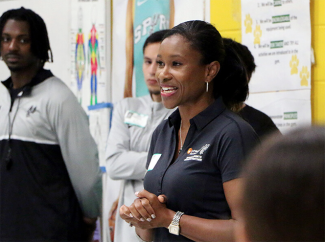woman speaking and smiling to a group in a classroom or community setting